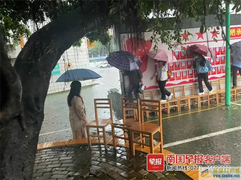 點贊！南寧一學校老師雨中赤腳蹚水，用凳子為學生搭橋(圖1)